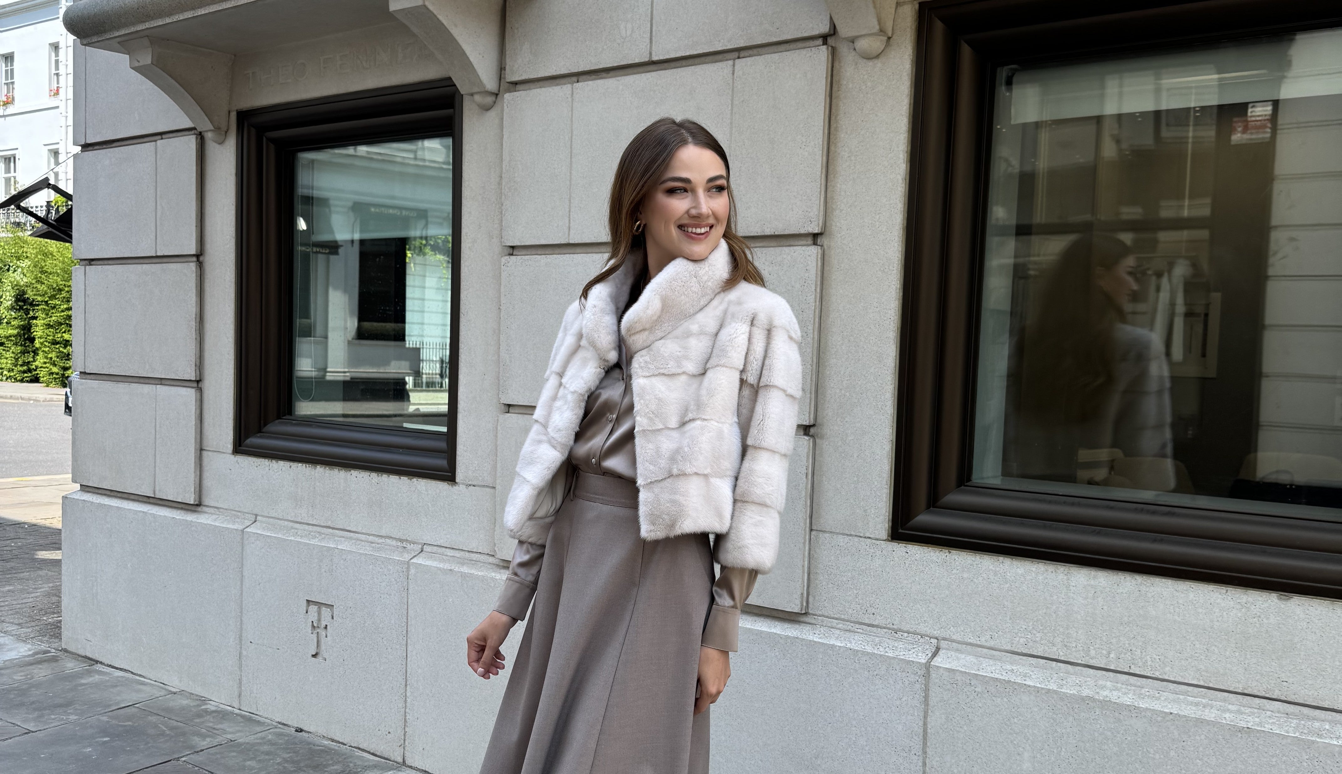 Woman in a fur vest standing in front of a building in London.