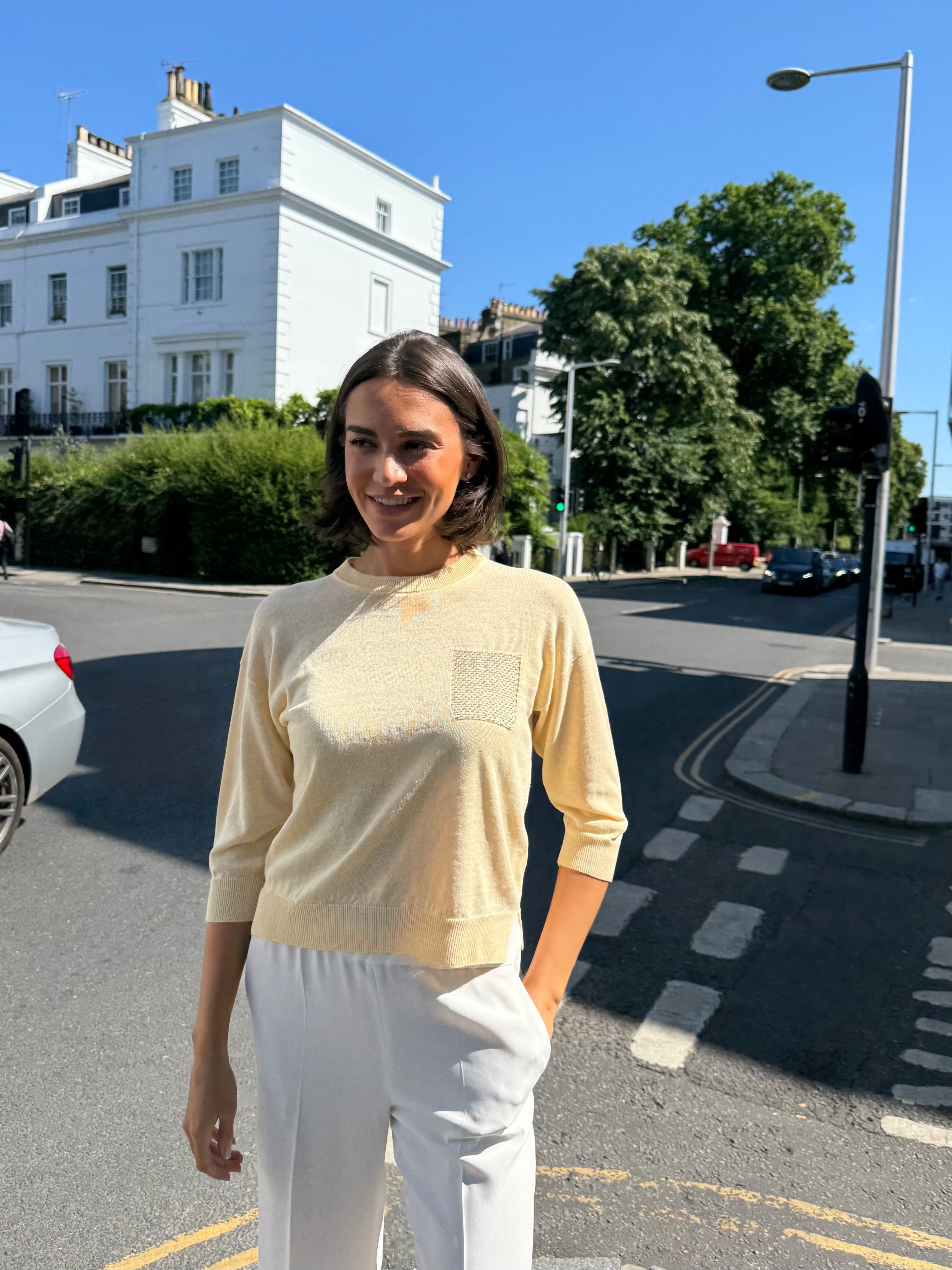 Yellow cashmere knit top with front pockets and knit texture.