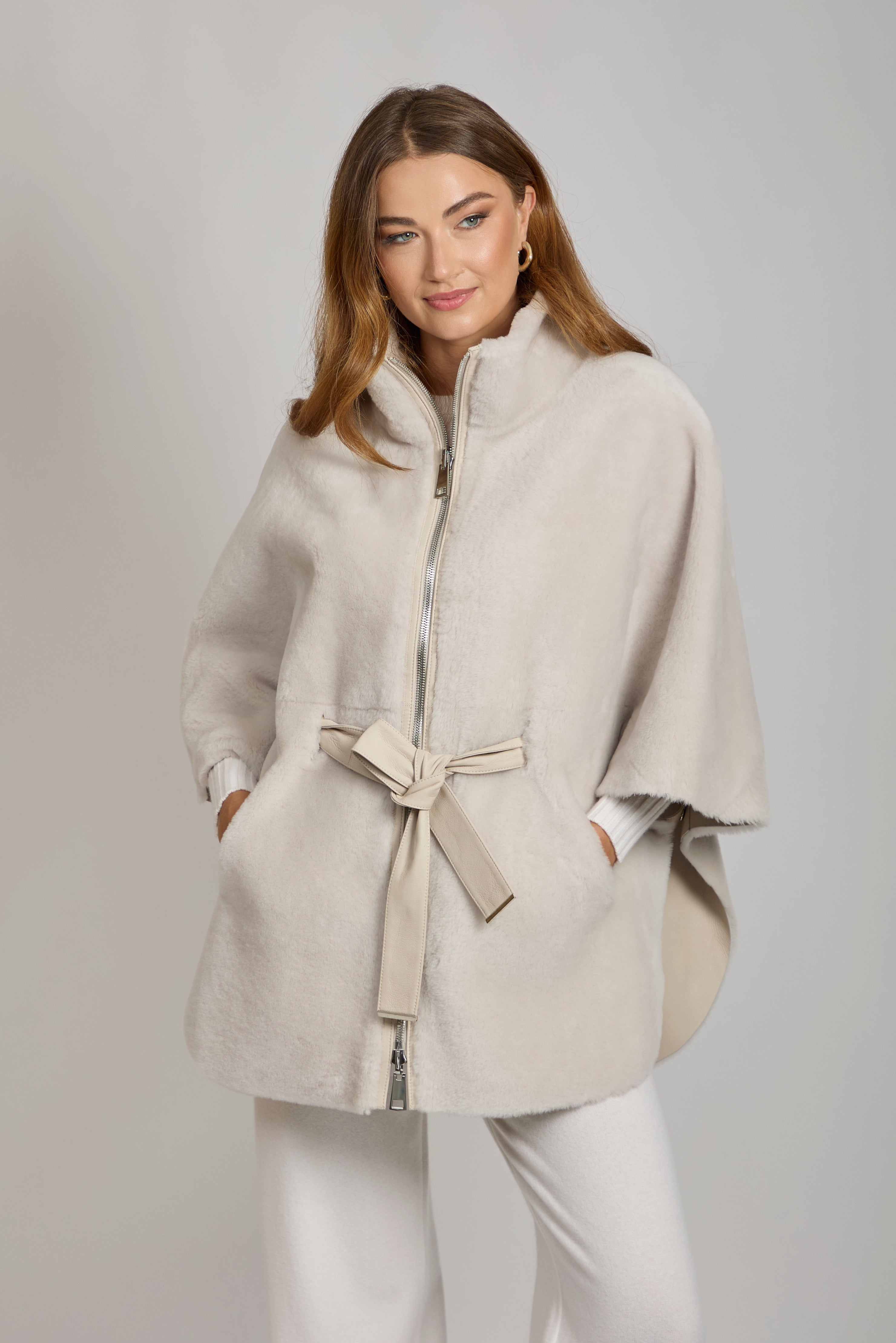 Reversible shearling cape in milk with plush texture, draped open-front silhouette and clean edges